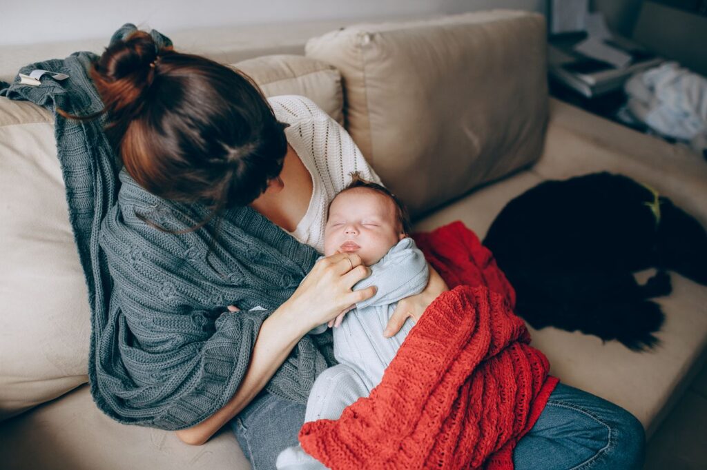 Madre descansando en el sofá con su bebé dormido