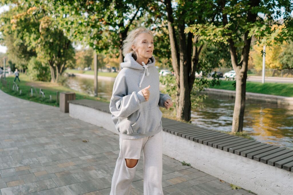 Mujer mayor corriendo por un paseo junto a un canal