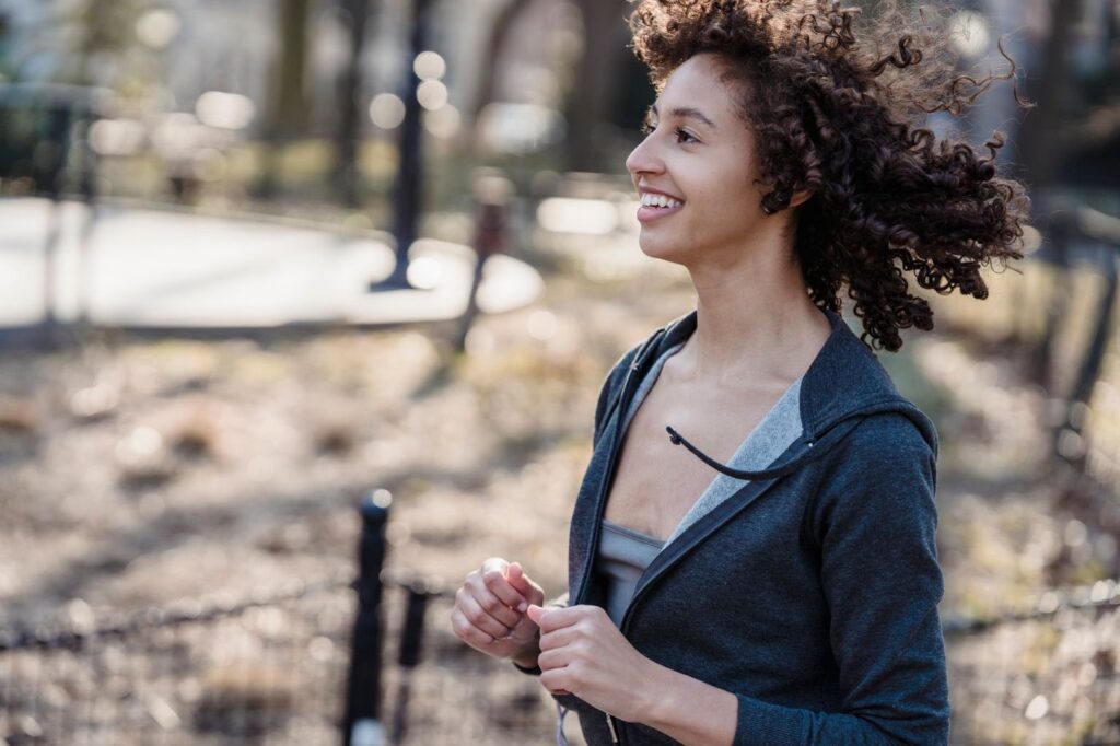 Mujer joven corriendo sonriente en un parque